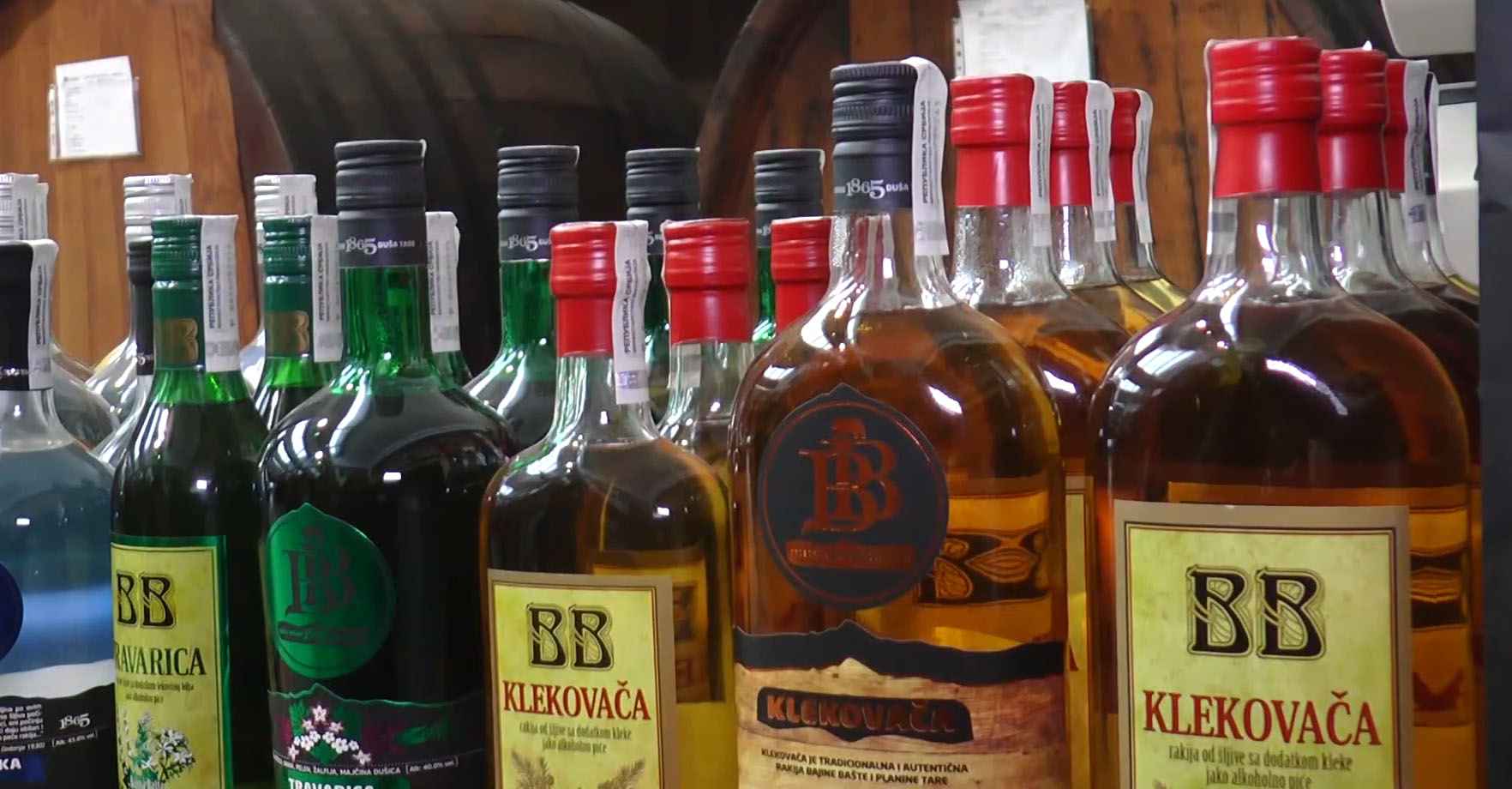 Više flaša različitih vrsta rakije BB, uključujući klekovaču i travaricu, poređanih na polici